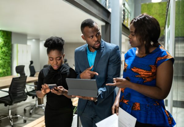 Three black african colleagues walking through coworking workspace strategizing on their way to boardroom business meeting