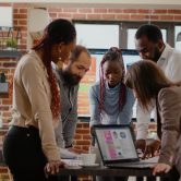 Team of colleagues analyzing charts on documents to plan project, working together to design presentation for business groth and development. Group of coworkers doing teamwork at company job.