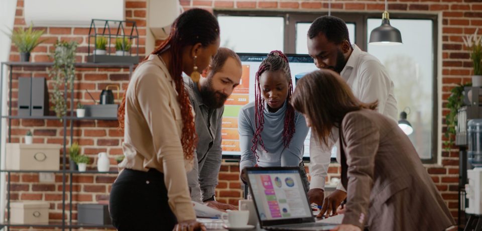 Team of colleagues analyzing charts on documents to plan project, working together to design presentation for business groth and development. Group of coworkers doing teamwork at company job.